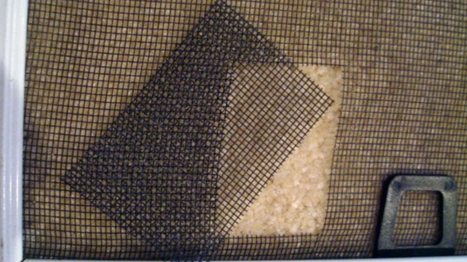 A close-up of a torn and frayed window screen on a Texas home, demonstrating the need for expert repair.