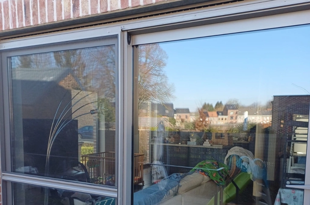 A homeowner effortlessly sliding open a repaired patio door in their Benbrook home, showcasing our successful track and roller replacement service.