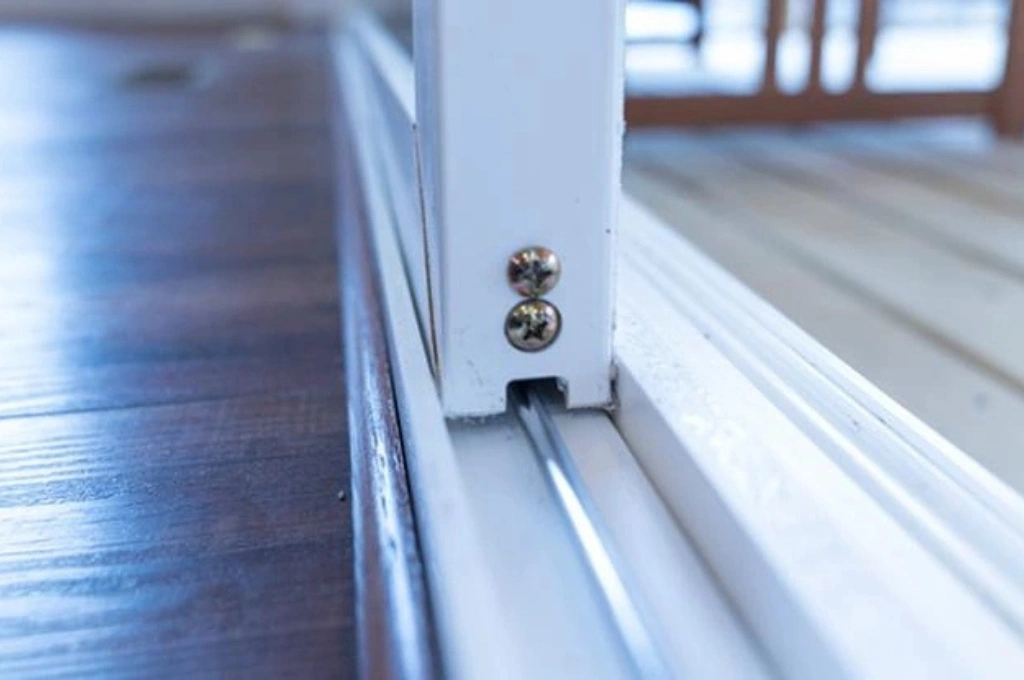 A certified technician completing a sliding glass door repair in a Garland, TX home, ensuring the door glides smoothly on its new rollers.