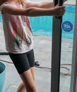 A certified technician performing an expert sliding glass door repair in Garland, TX, by replacing the rollers for a smooth glide.