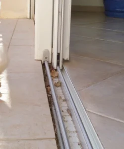 A close-up of a technician's hands expertly replacing the rollers on a sliding glass door repair El Paso home.