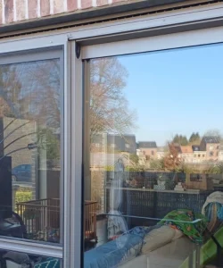 A homeowner effortlessly sliding open a repaired patio door in their Benbrook home, showcasing our successful track and roller replacement service.
