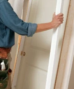 A skilled technician from Windows And Doors Repair LLC meticulously repairing a door jamb and aligning the hinges.