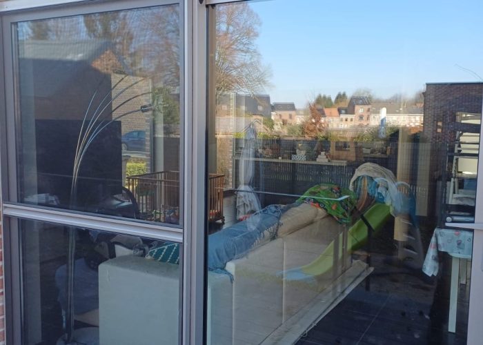 Small, enclosed outdoor space with white perimeter walls, a single window, a round gray planter, and lush, long green grass, in Dallas